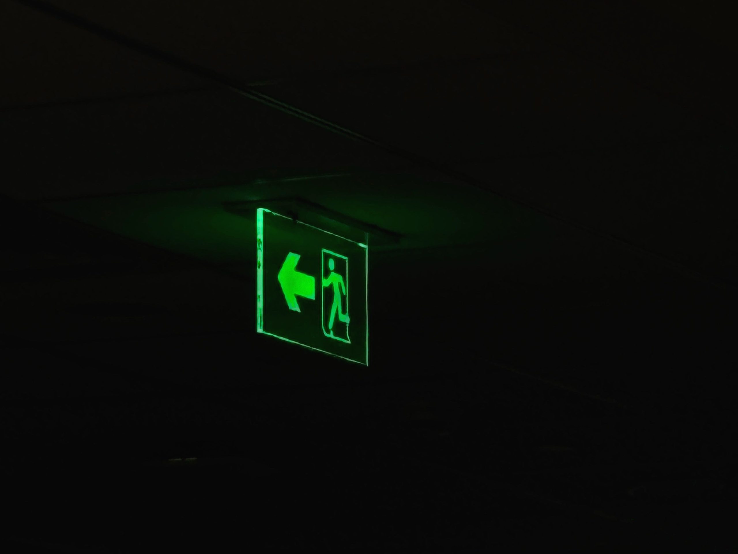 Panneau de sortie vert illuminé dans un couloir sombre