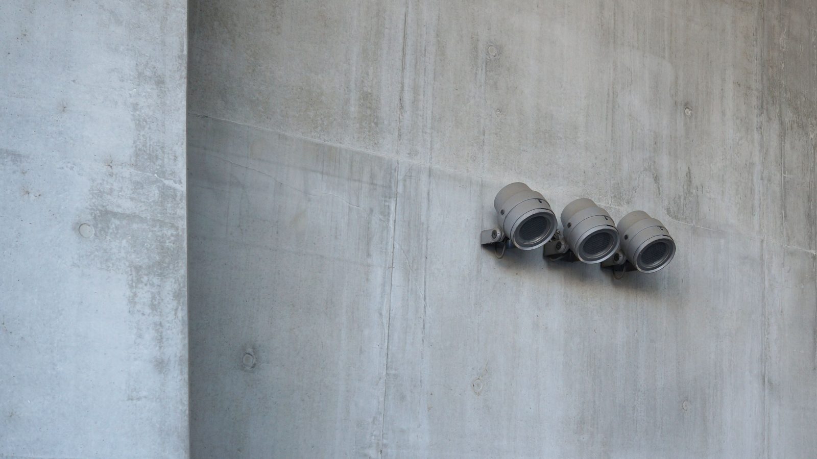 Trois projecteurs industriels fixés sur un mur gris