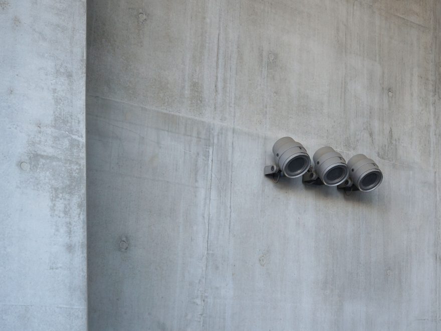 Trois projecteurs industriels fixés sur un mur gris