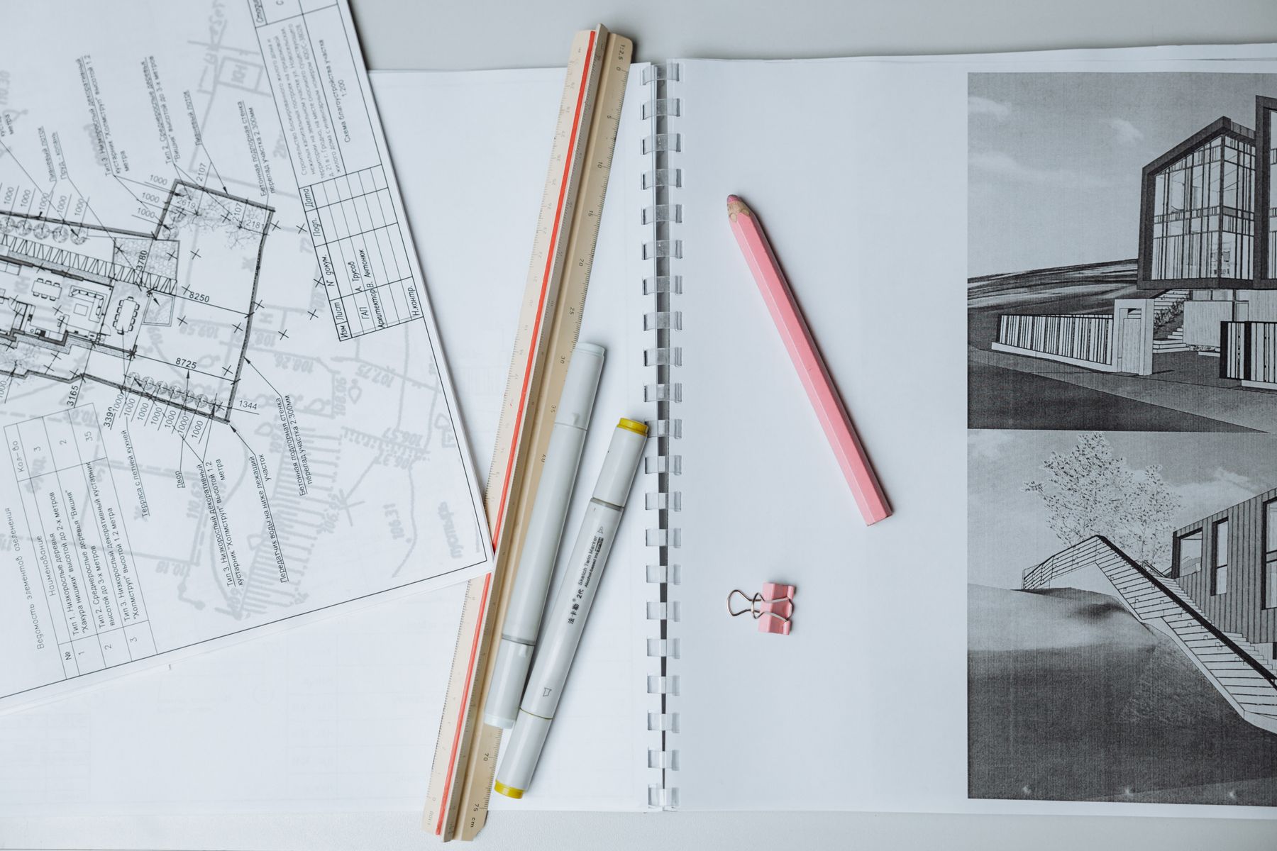 Plans architecturaux, règle et crayon rouge sur table blanche